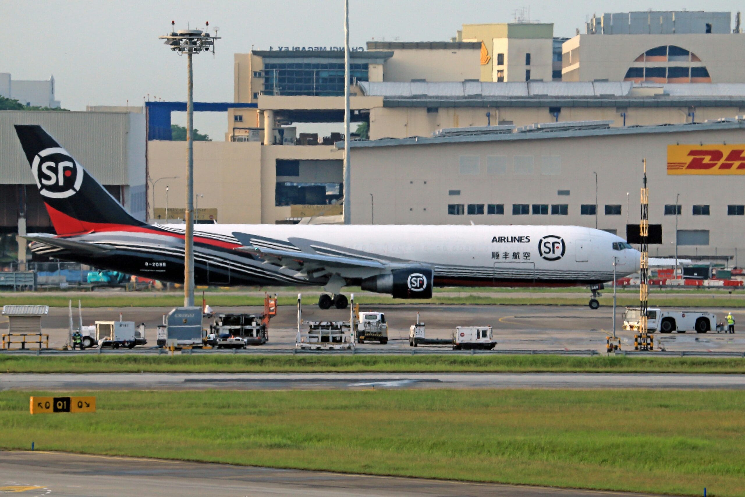 SF Airlines cargo aircraft parked on the airport tarmac near a DHL building.